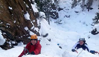 Two ice climbers summiting their cliff.